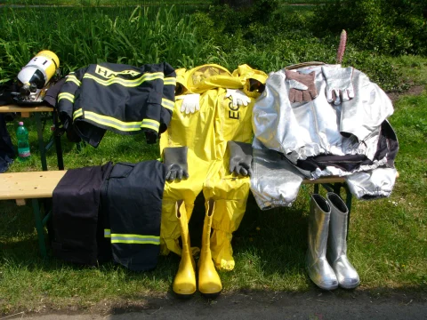 Firefighter turnout gear, hazmat suit, and proximity suit laid out on a bench